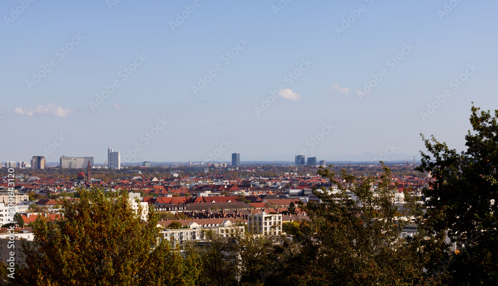 Munich skyline photographed from the Olympia hill in Munich Olympiapark on a clear day with the Alps on the background