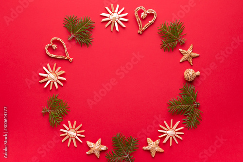 Christmas natural wood decorations and pine tree frame on red background  copy space. Flat lay  christmas card with ornaments from ecological materials  top view