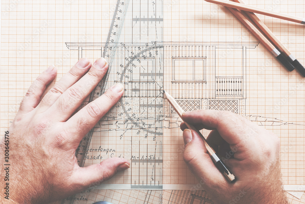 Designer/architect drawing a cabin on drawingboard. Architecture