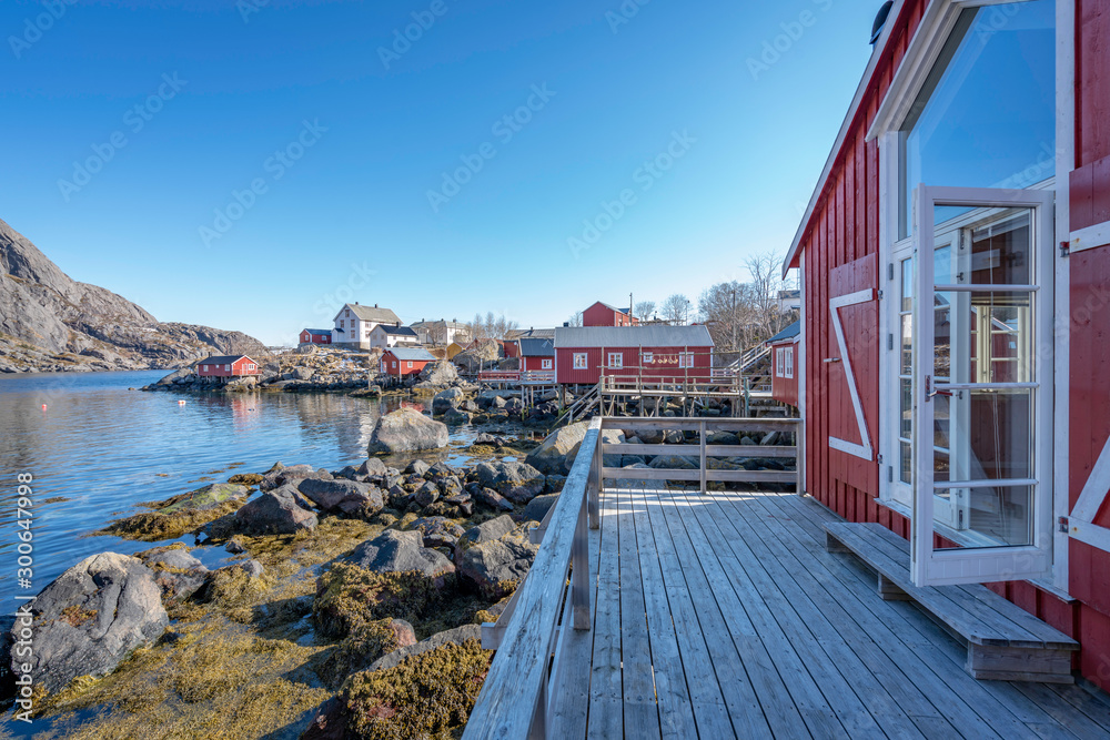 Nusfjord fishing village and red fishing huts in Lofoten islands in Norway. Buildings, architecture, blue sky, holiday, travel and lifestyle concept.