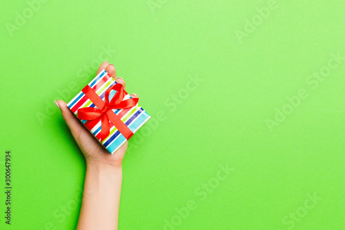 Top view of female hands holding christmas or other holiday handmade present box package in the palms, flat lay table background with copy space