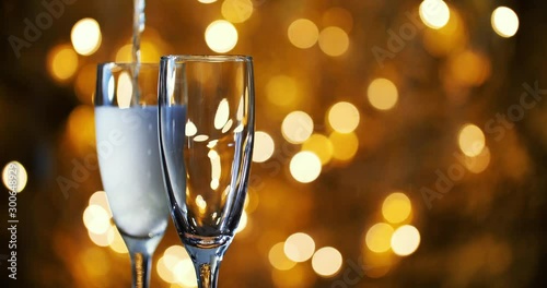 Champagne is poured into glasses against the background of New Year 's garland.