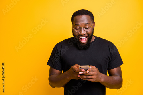 Photo of toothy mixed-race handsome funny man brunet haired in t-shirt overjoyed about receiving positive notification of feedback isolated vivid yellow color background