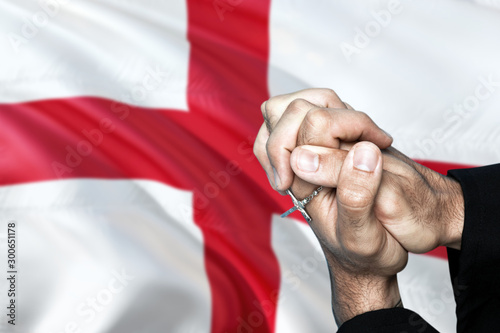 England flag and praying patriot man with crossed hands. Holding cross, hoping and wishing.