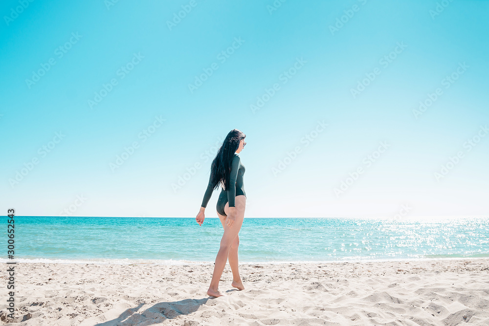 Girl with black hair is walking along the beach in a bodysuit Girl with black hair is walking along the beach in a bodysuit