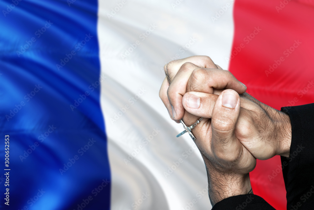 France flag and praying patriot man with crossed hands. Holding cross, hoping and wishing.