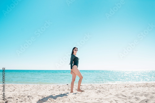 Girl with black hair is walking along the beach in a bodysuit
