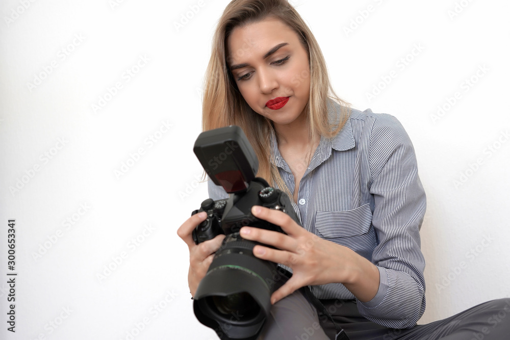 Young beautiful blonde holding a big camera in her hands, white background Young beautiful blonde holding a big camera in her hands, white background