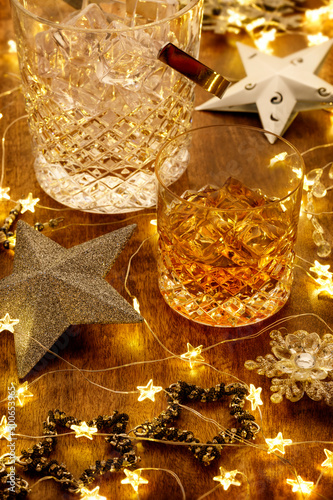 Crystal glass of whisky and a whisky decanter with christmas lights, baubles and silver stars
