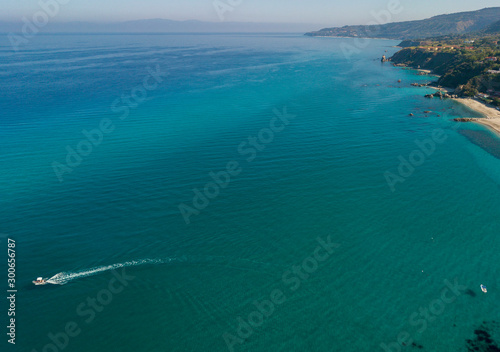 Aerial view of a motor boat sailing near the rocks and the beach of Tropea  Calabria  Italy