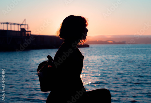 profile silhouette of a woman sitting by the water during sunset in san diego