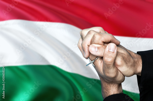 Hungary flag and praying patriot man with crossed hands. Holding cross, hoping and wishing.