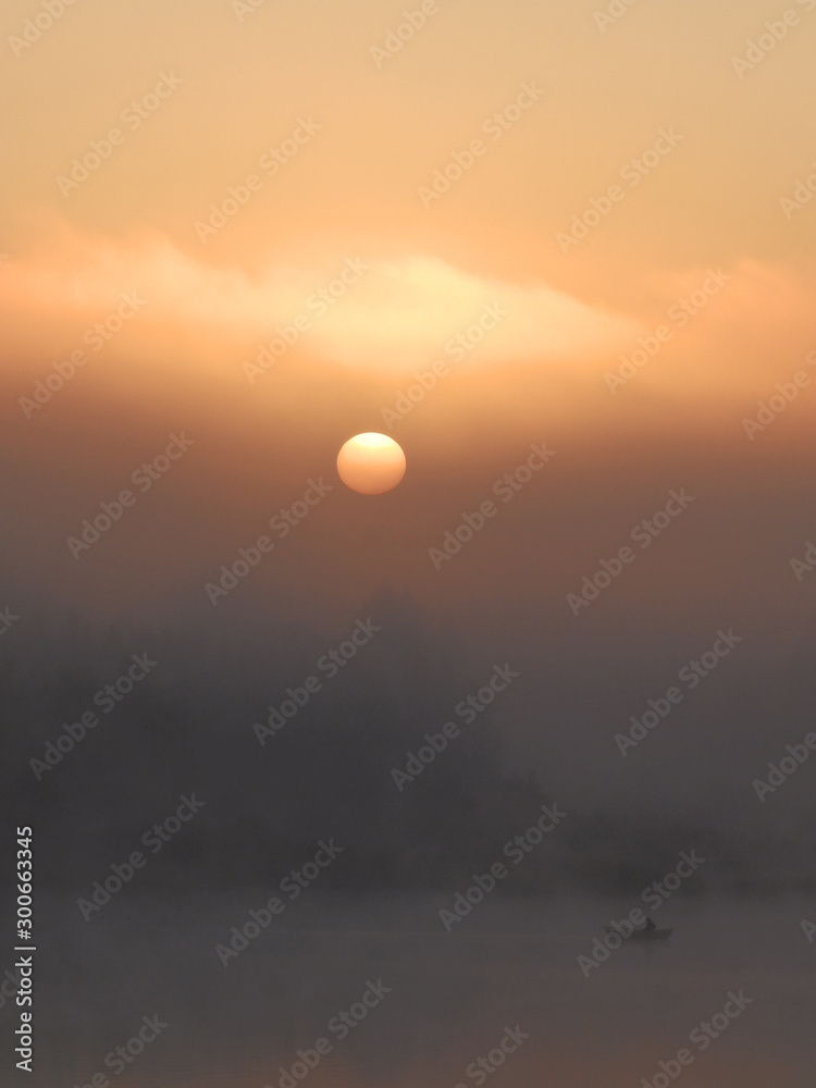 Beautiful, colorful landscape of a foggy lake during sunrise. Misty dawn in the lake. Bright sun over lake. Beautiful, colorful landscape of a foggy lake during sunrise. Misty dawn in the lake. Bright sun over lake.