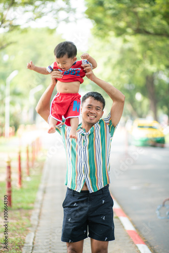 Baby boy playing with dad in green public morning park