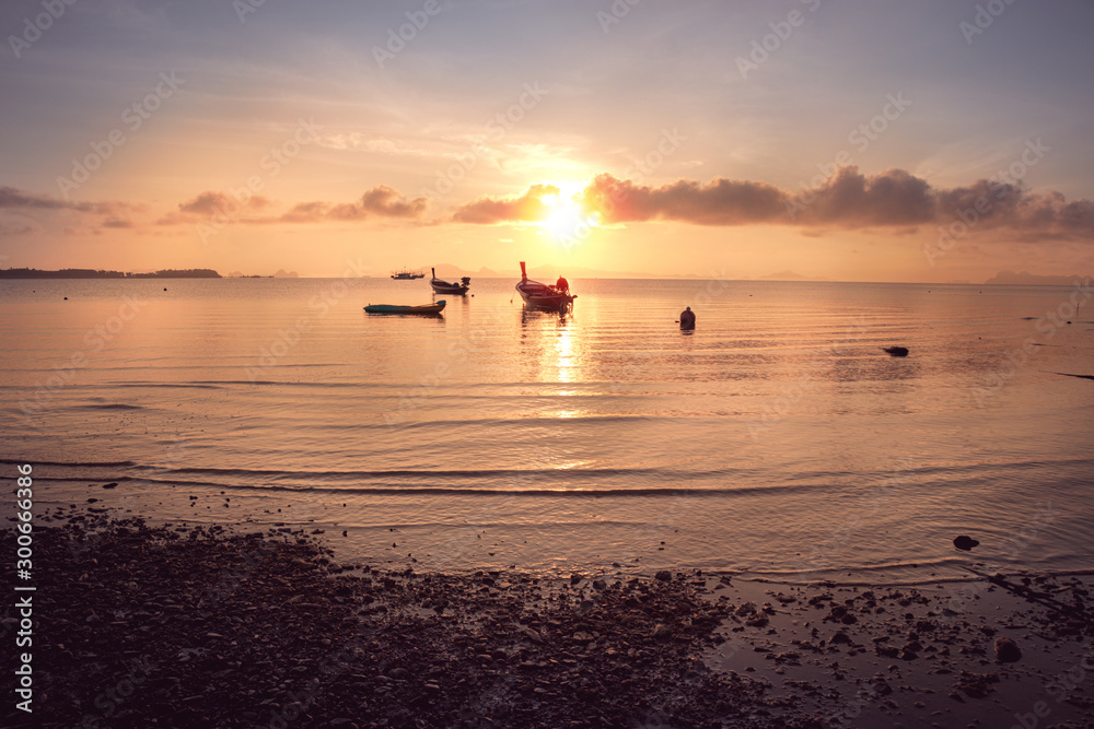 small motor fishing boat of the island villagers for tourists mooring along at the beach in sunrise, South of Thailand small motor fishing boat of the island villagers for tourists mooring along at the beach in sunrise, South of Thailand
