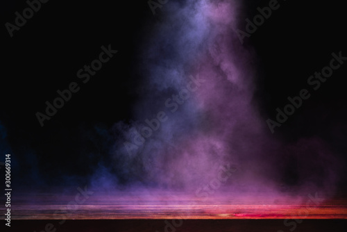 empty wooden table with colorful smoke float up on dark background © Thitiwat.Day