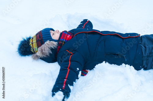 boy 5 years old in winter lying in the snow