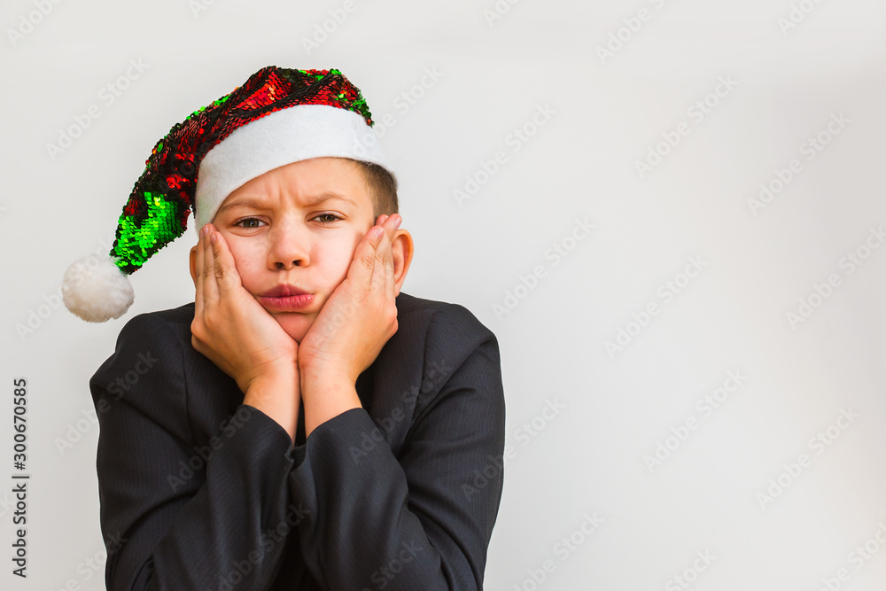 disgruntled teenage boy in Santa hat on white isolated background disgruntled teenage boy in Santa hat on white isolated background