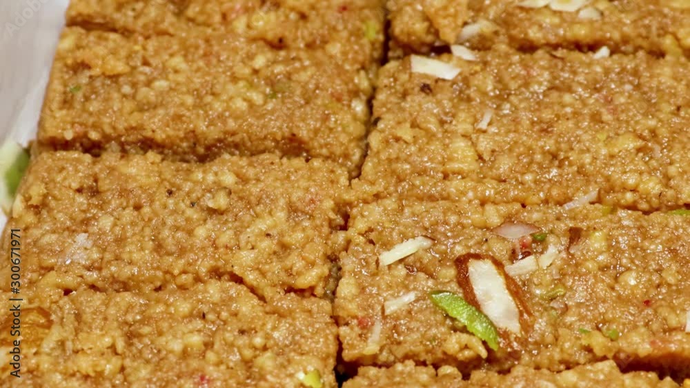 closeup shot of Indian sweet name of mawa barfi (sweetened gram flour fudges made with Ghee, and flavored with saffron and almonds) a Traditional Gujarati Sweet in, Gujarat, India closeup shot of Indian sweet name of mawa barfi (sweetened gram flour fudges made with Ghee, and flavored with saffron and almonds) a Traditional Gujarati Sweet in, Gujarat, India
