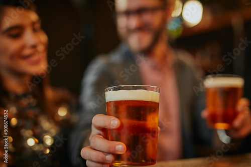 Man standing in group and giving beer to a friend. Irish pub interior. Nightlife.