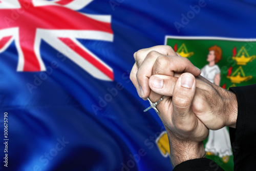 British Virgin Islands flag and praying patriot man with crossed hands. Holding cross, hoping and wishing.