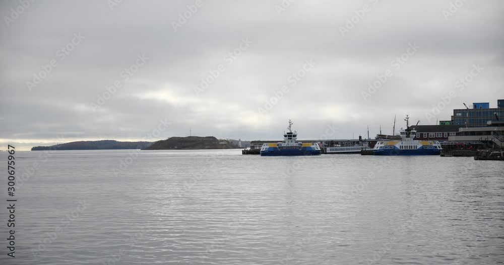Passenger ferries arriving and departing from the terminal on the harbour with island and lighthouse in the background. Passenger ferries arriving and departing from the terminal on the harbour with island and lighthouse in the background.