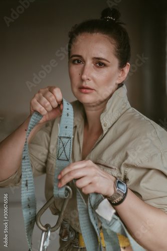 Beautiful girl in overalls holds mounting belt photo