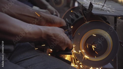 worker grading metal part on the grinder that generating sparkes  that looks cool photo