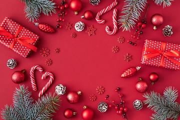 Flat lay frame with red christmas balls, spruce branches and gift box on a red background