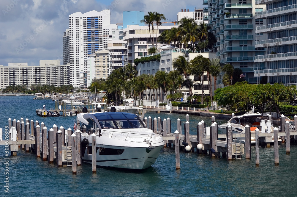 High-end cabin cruiser moored at a small marina in Miami Beach with luxury condo buildings overlooking the intra-coastal waterway in the background .