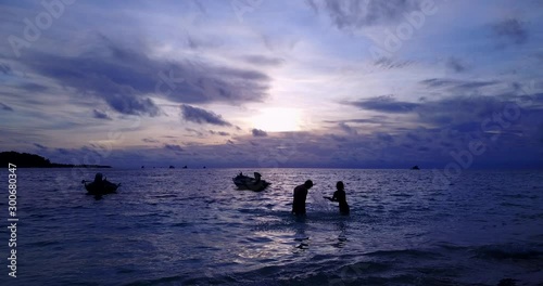 summer love concept. Young romantic couple having fun in the tropical sea, laughing and splashing water on each other on purple sunset photo