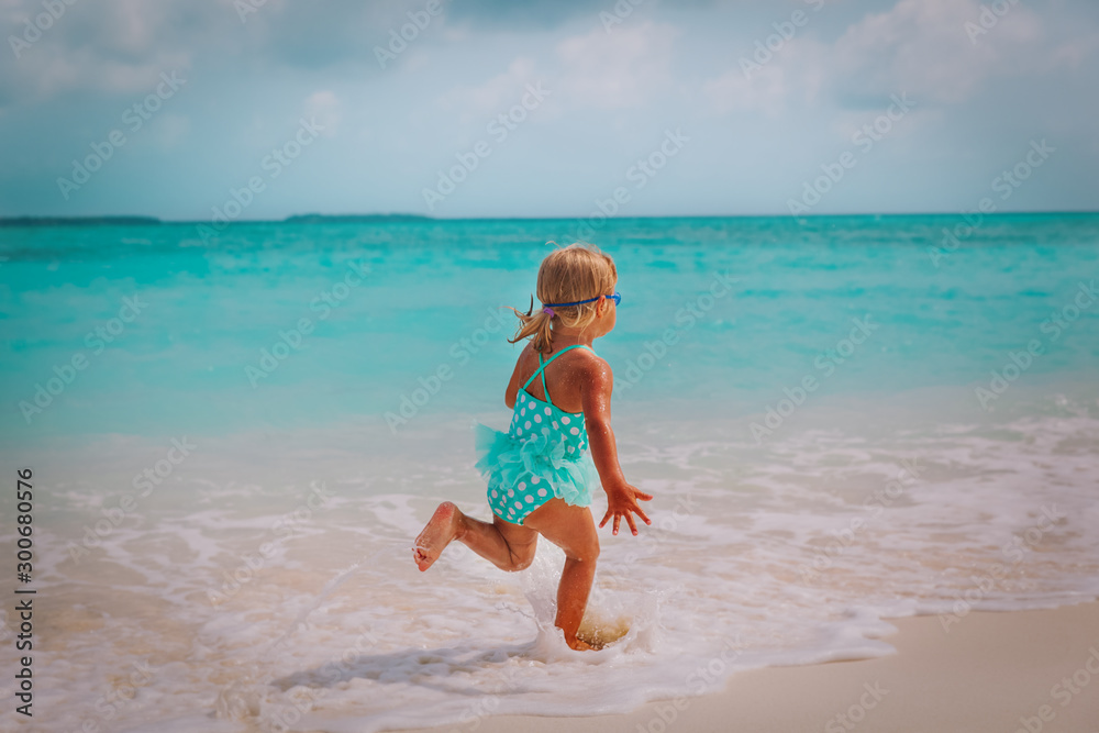 happy little girl run and play with waves on tropical beach happy little girl run and play with waves on tropical beach