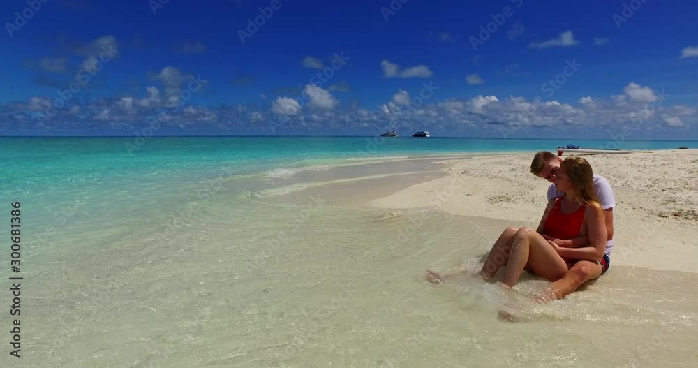 Boy kissing his girlfriend sitting on white sand of exotic beach, washed by sea waves in Bora bora Boy kissing his girlfriend sitting on white sand of exotic beach, washed by sea waves in Bora bora