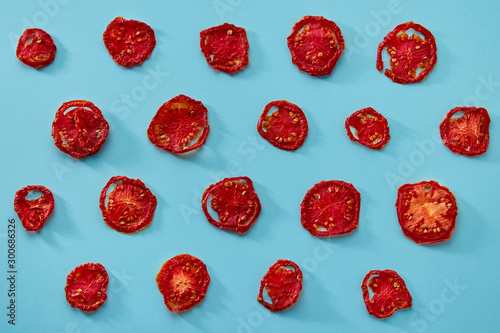 Dried tomatoes on colored background. Pattern of dried tomatoes. Sundried or dried tomato slices, macro, close up.