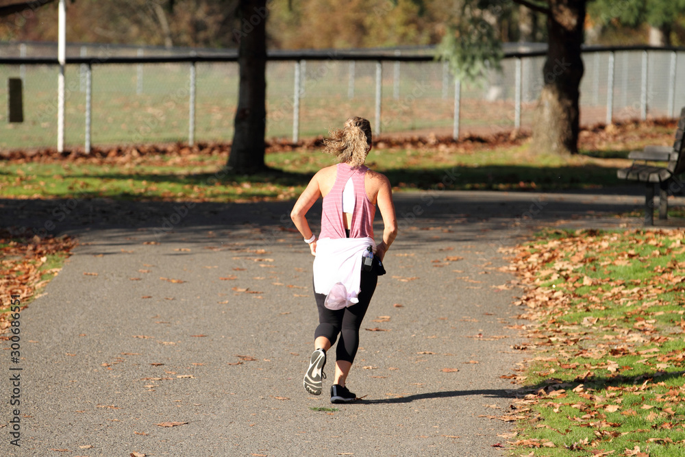 Fototapeta premium Female runner on the path at a park on a sunny day.