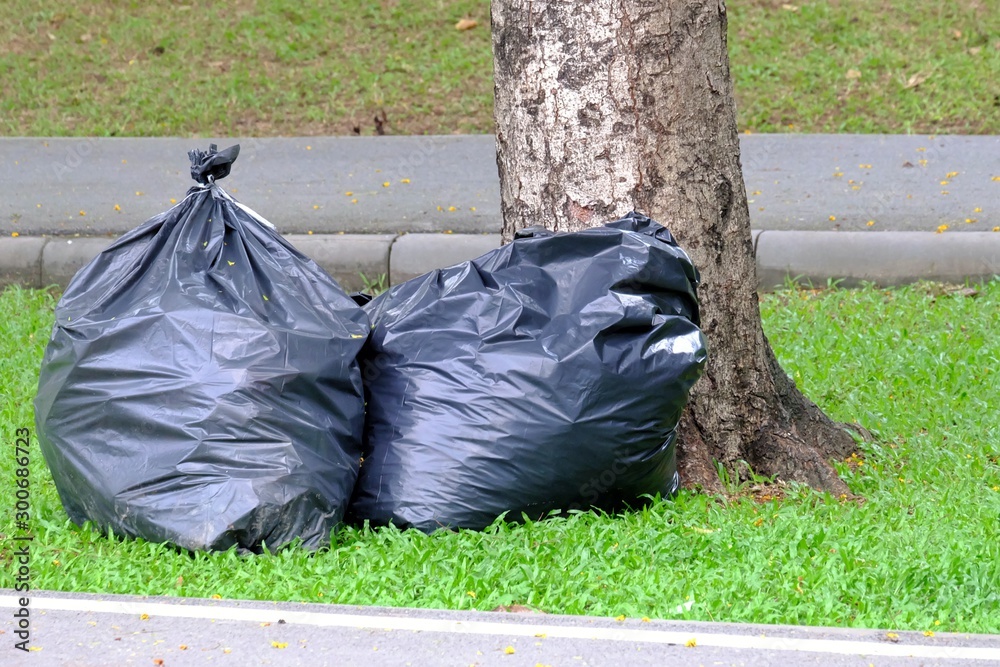Large plastic trash bags on the sideway at the green park with tropical