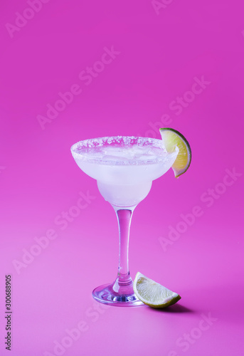 Lime margarita alcoholic cocktail with silver tequila, liqueur, lime juice, sugar syrup, salt and ice, festive trendy lilac background, copy space