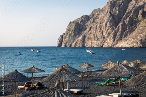 Fototapeta Naklejka Na Ścianę i Meble -  Kamari beach in Santorini. Beach parasoles, mountain and fishing boats. Relaxing, beach, holiday, vacation, santorini, travel, summer concept.