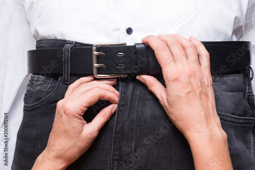 Woman hands unbelt leather belt on man jeans
