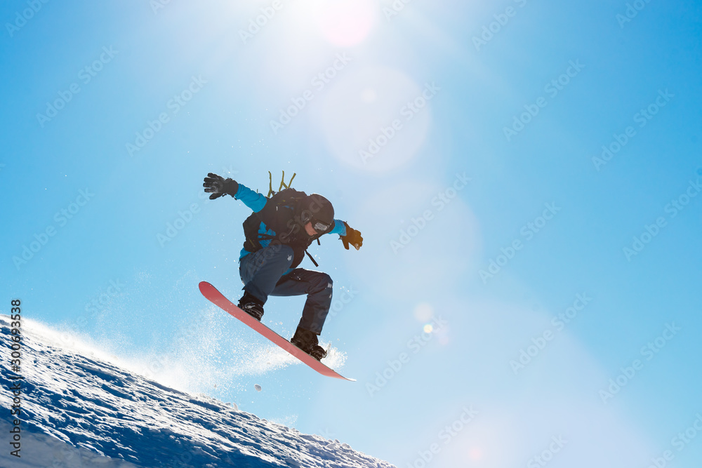 Snowboarder Riding Red Snowboard in Mountains at Sunny Day. Snowboarding and Winter Sports