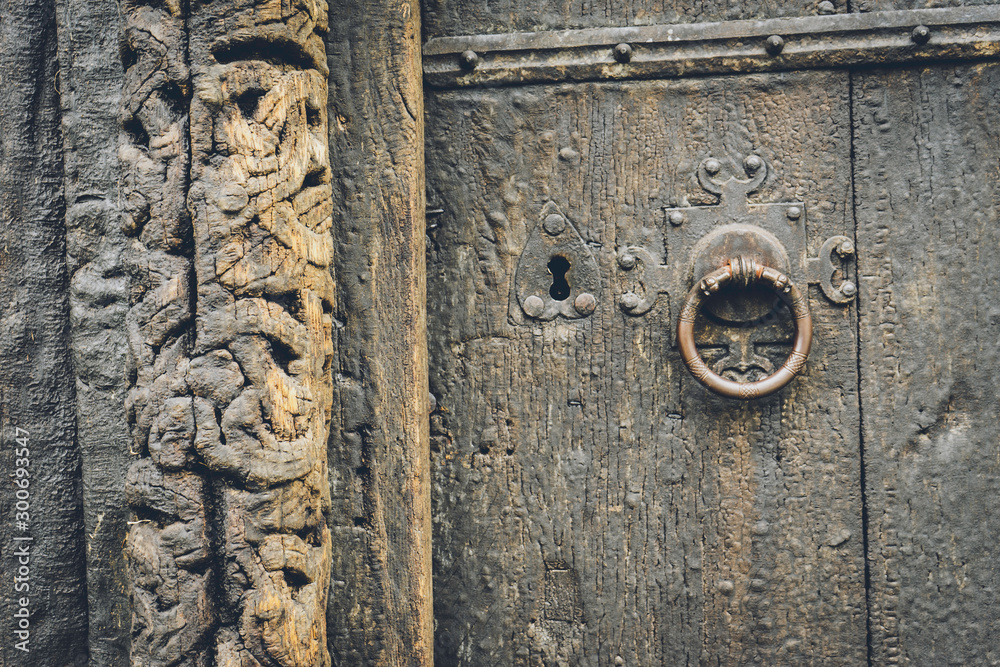Old ancient wooden door details with carvings, metal keyhole and door knob. Texture, pattern