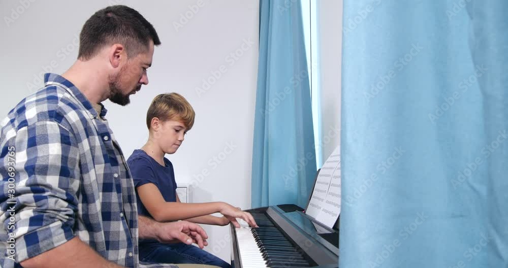 Man teaching boy to play piano in room