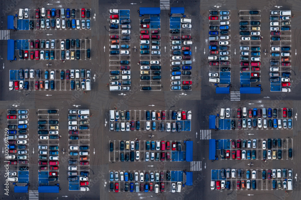 Aerial top view of parking with many cars. Many cars are parked in a parking lot with white markings. Parking places with vehicles pattern. Aerial top view of parking with many cars. Many cars are parked in a parking lot with white markings. Parking places with vehicles pattern.