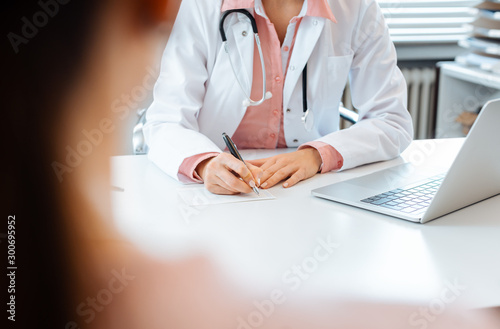 Obraz na plátně Close-up of doctor taking notes while having appointment with patient