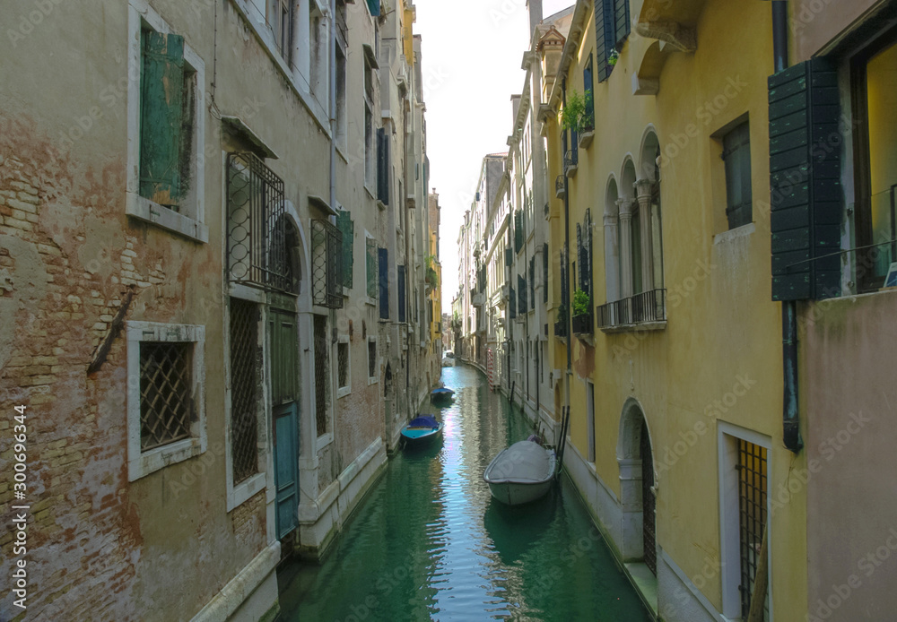 Canal entre casas en Venecia con botes un dia soleado