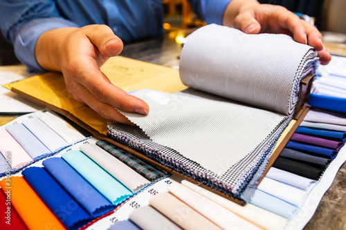 tailor choosing a fabric in swatch for his customer photo