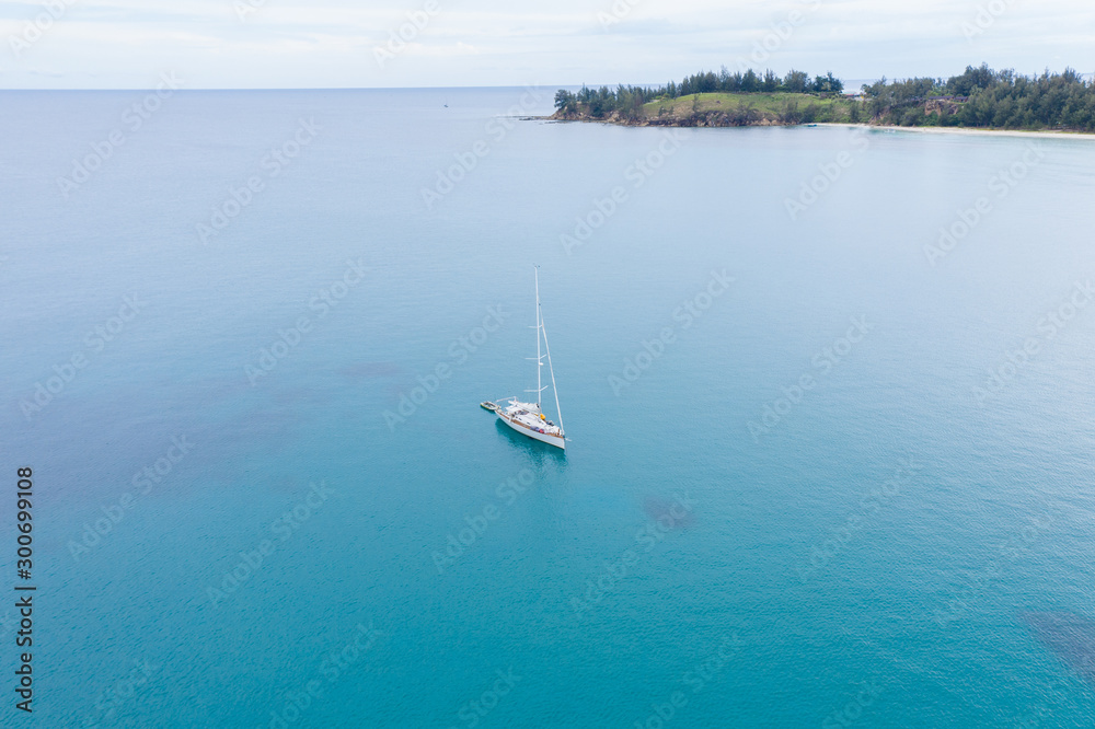 Fototapeta premium Aerial view of white Yacht in deep blue sea with beautiful landscape view in Kudat, Sabah, Borneo