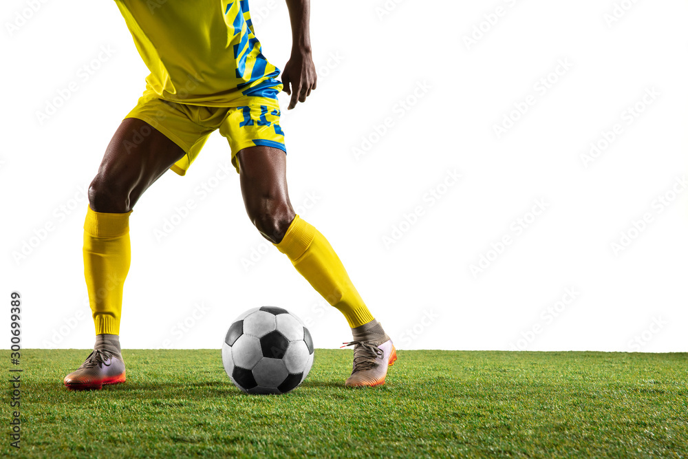 Obraz premium Professional african-american football or soccer player of yellow team in motion isolated on white studio background. Fit man in action, excitement, emotional moment. Concept of movement at gameplay.