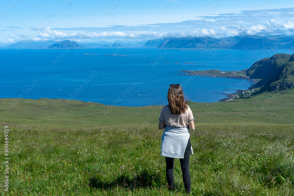 Girl looking at the beautiful scenery from the islands of Runde in Norway during summer holiday. Vacation, sunny, blue sky, girl, hiking concept.