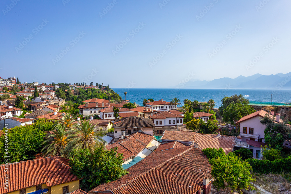 Beautiful aerial view of old red roofs of many small houses, peaceful blue sea water and foggy mountains. Antalya city, Turkey country. Horizontal color photography.